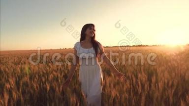 在温暖的<strong>夏日</strong>傍晚，女孩触摸成熟的麦穗。 穿着白色衣服的快乐女孩带着一缕<strong>麦子</strong>走在田野上